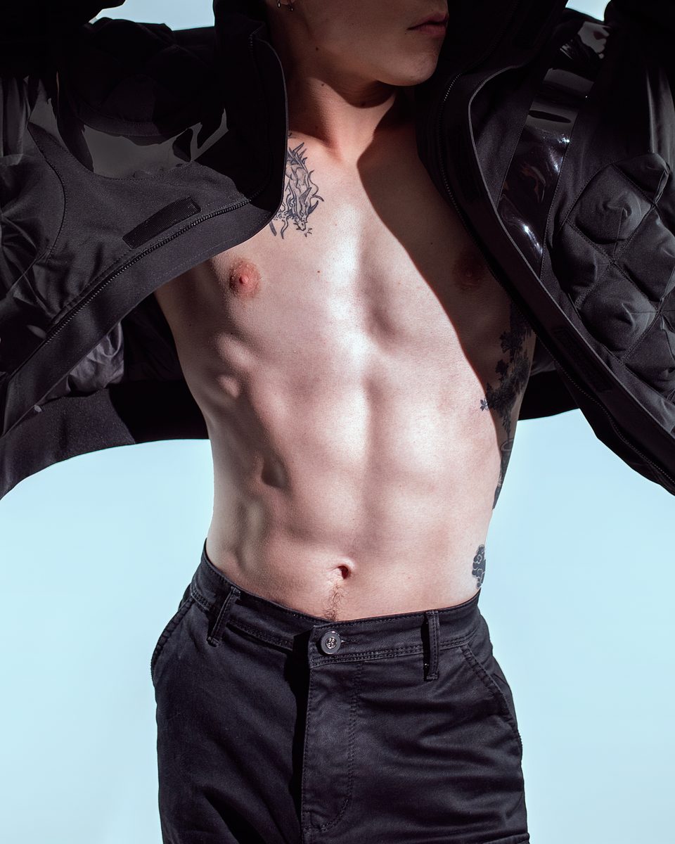 A model in an open black quilted jacket and black cargo trousers.