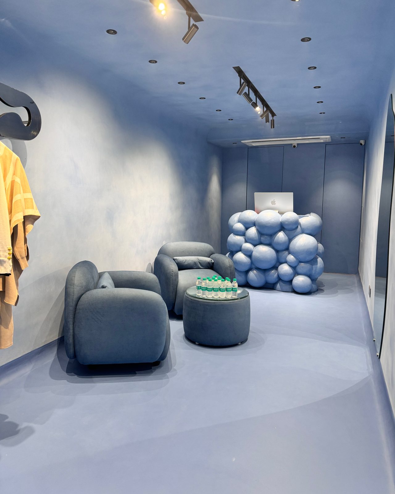 Two deep blue armchairs and a round table in front of a counter built from blue spheres.
